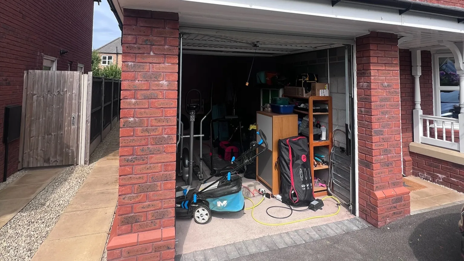 Single garage before conversion, full of bikes, a lawnmower and storage